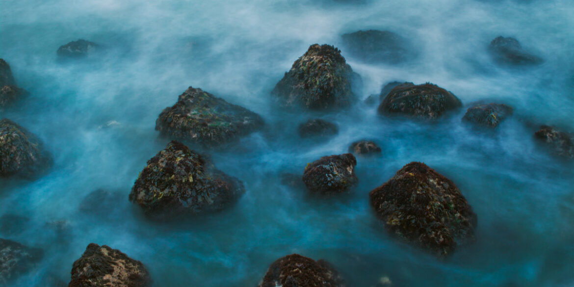 A long exposure photo of a rocky seashore on the California coast